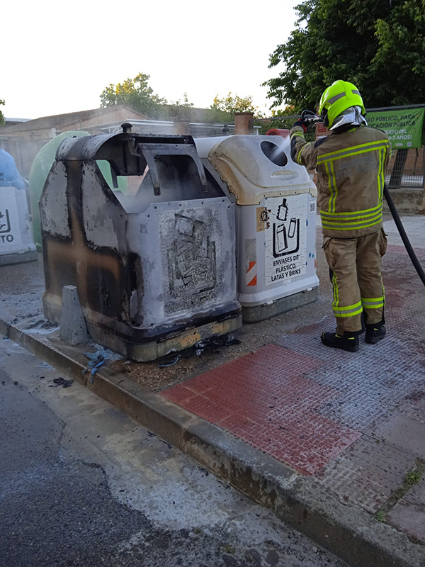 Bombero apagando el incendio en uno de los contenedores afectados